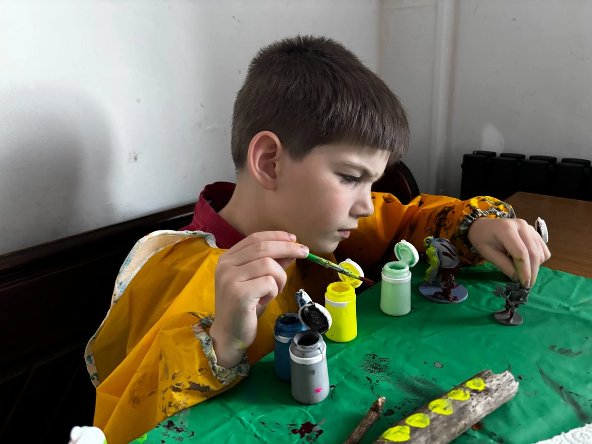 Young Creator painting a large tabletop creature as part of a making activity