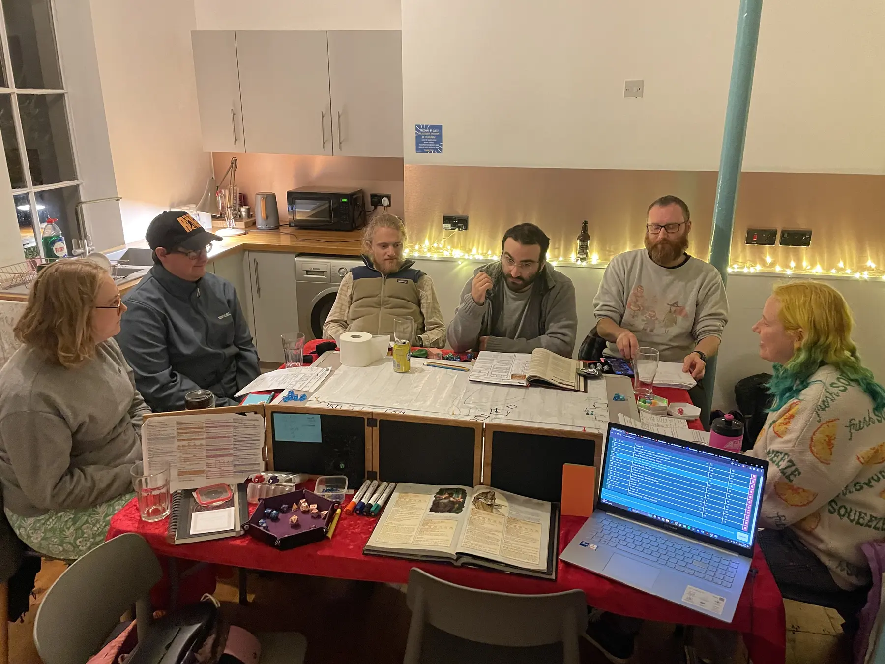 A mixed adult group gathered around a map-filled tabletop adventure