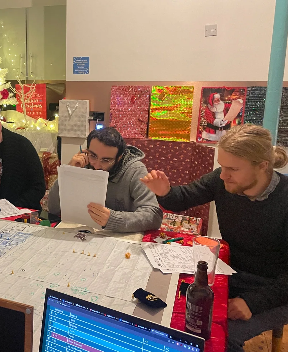Two players engaged in the same festive hosted tabletop event from the opposite side of the table