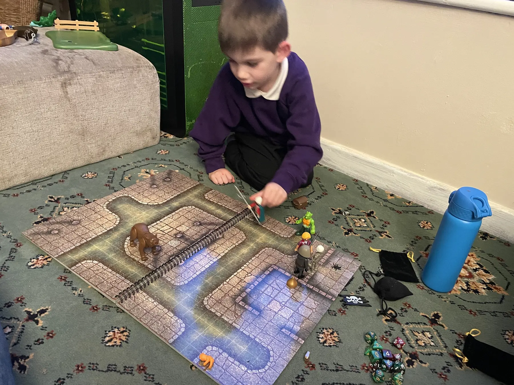 A young player moving miniatures through a floor-based tabletop map