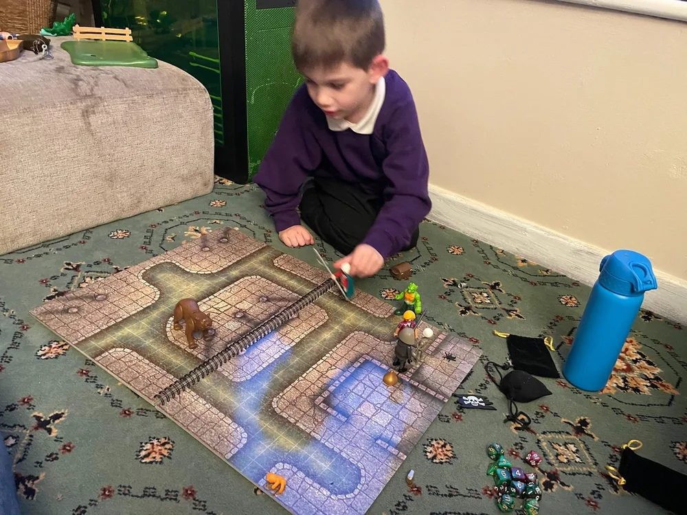 A young tabletop player moving miniatures across a map