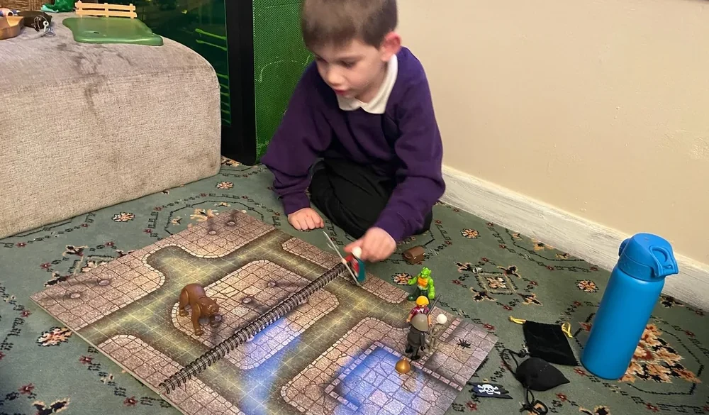 Young Explorer moving a miniature through a tabletop map during play