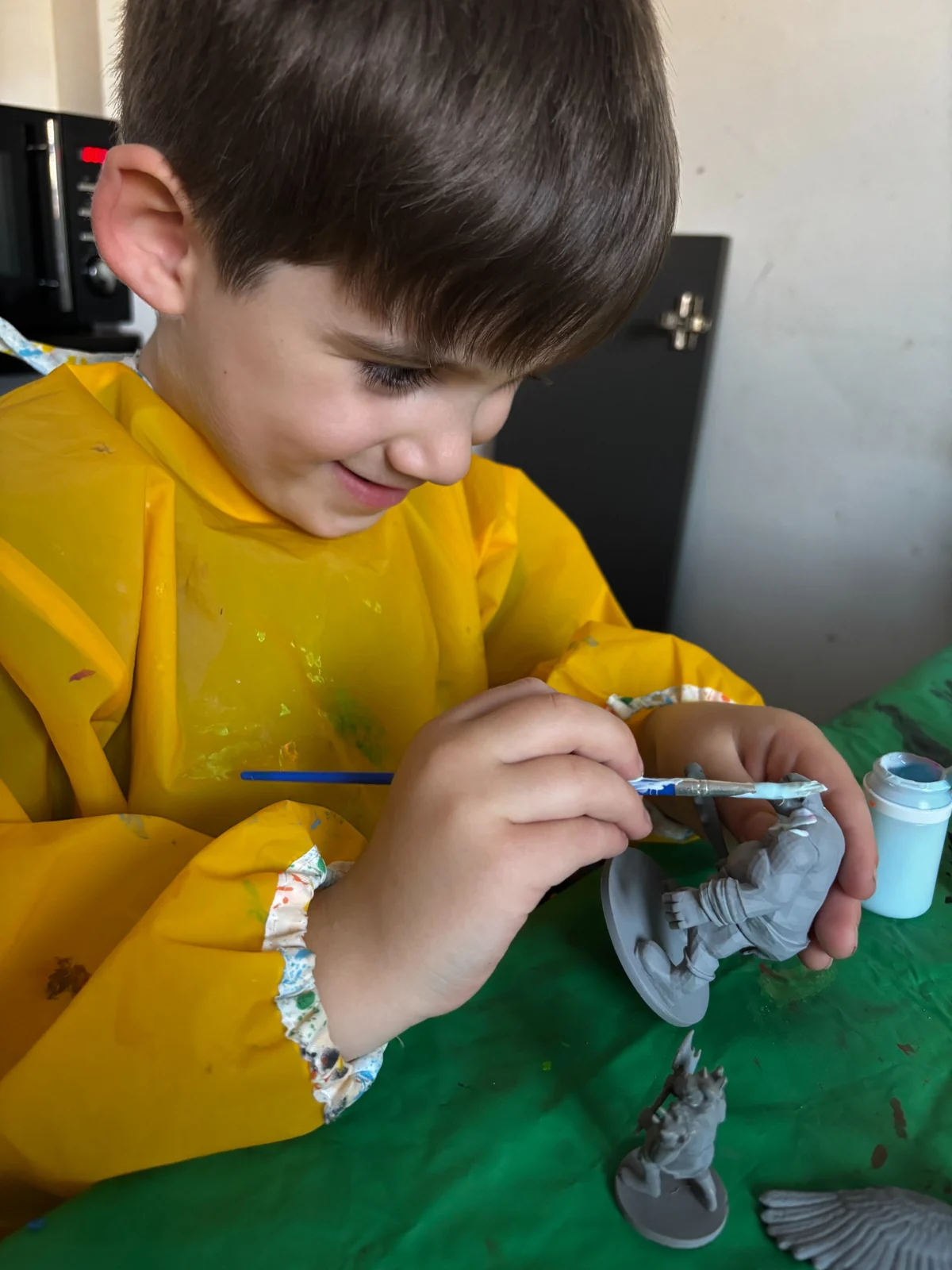 Young Creator smiling while painting a tabletop miniature